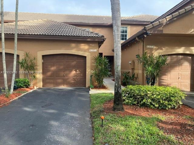 A two-story tan townhouse features two garage doors and a paved driveway — 1384 Veracruz Ln # 7, Weston FL 33327, WESTON, FL