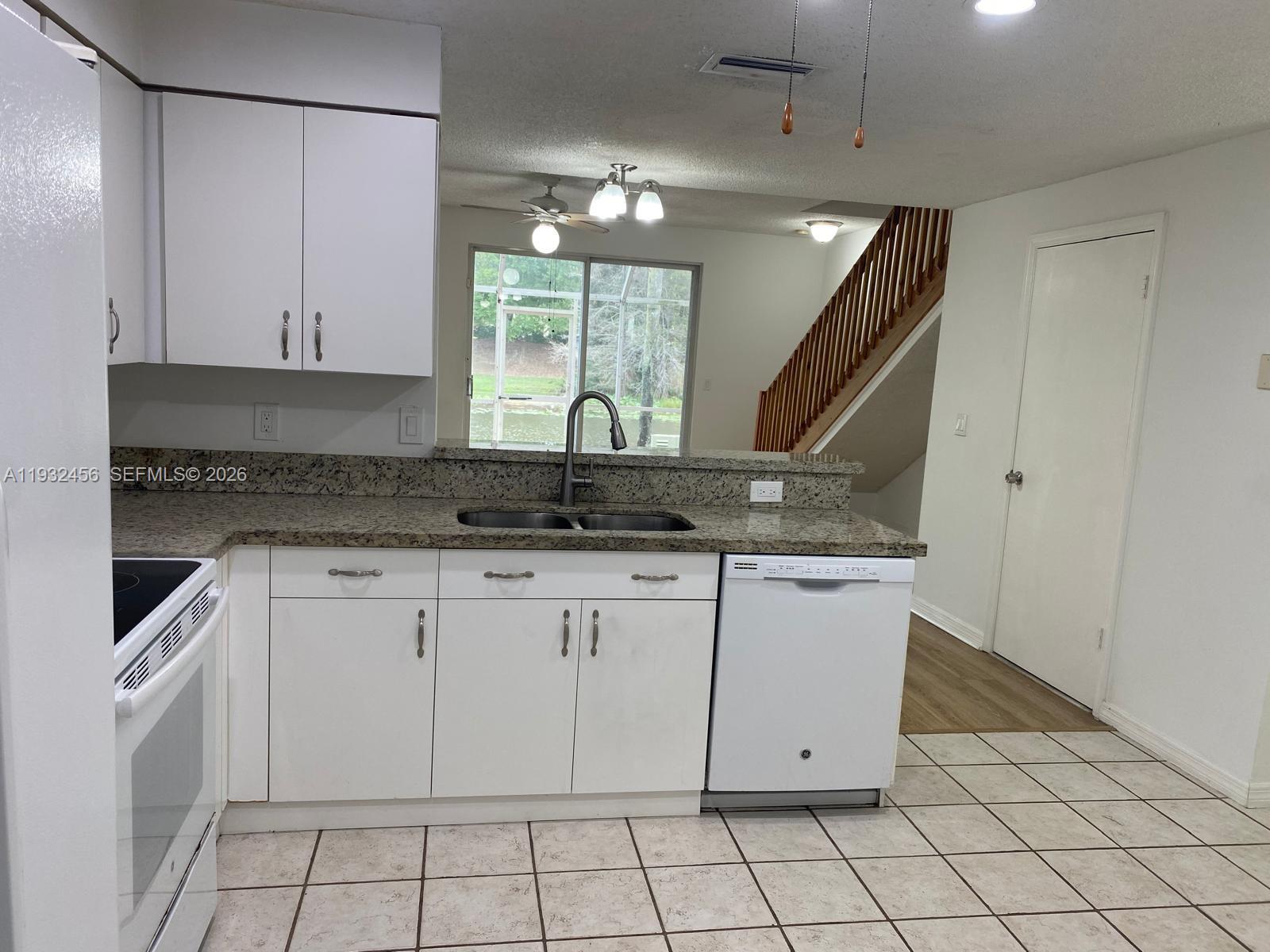 A kitchen features white cabinets, granite countertops, a double sink, and tile flooring — 1384 Veracruz Ln # 7, Weston FL 33327, WESTON, FL