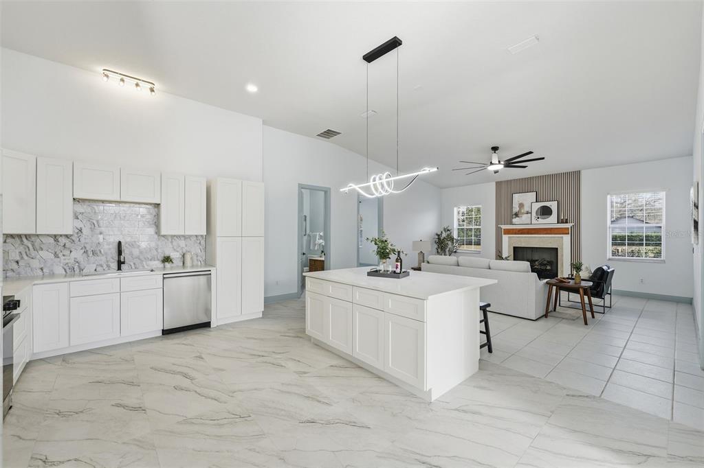 A modern open-concept kitchen and living area with white cabinets, marble floors, and a fireplace — 4873 NE 64TH AVENUE, SILVER SPRINGS, FL