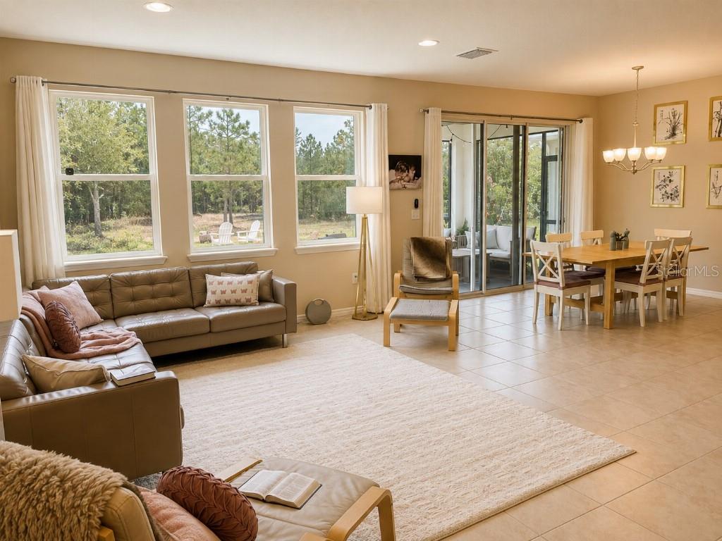 A living and dining area with tile floors, a leather sectional, and large sliding glass doors — 2296 MIDNIGHT PEARL DRIVE, SARASOTA, FL
