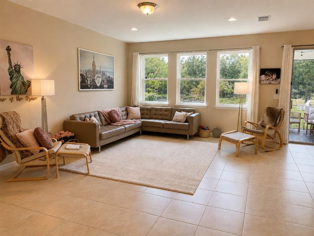 A living room features a beige sectional sofa, two armchairs with ottomans, and large windows — 2296 MIDNIGHT PEARL DRIVE, SARASOTA, FL