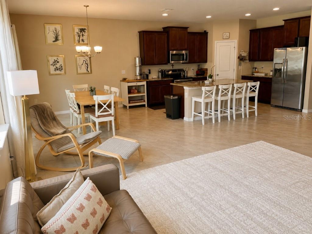 An open-concept kitchen with dark wood cabinets, a dining area, and a living space — 2296 MIDNIGHT PEARL DRIVE, SARASOTA, FL