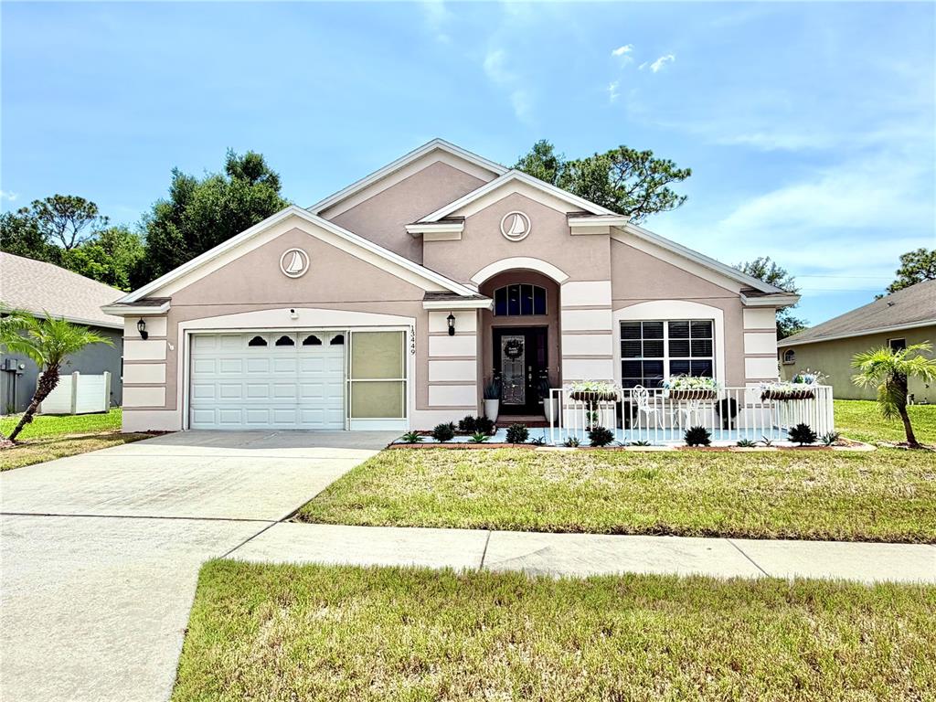 A single-story house with a beige stucco exterior, a two-car garage, and a front porch — 13449 MEADOW GOLF AVENUE, HUDSON, FL