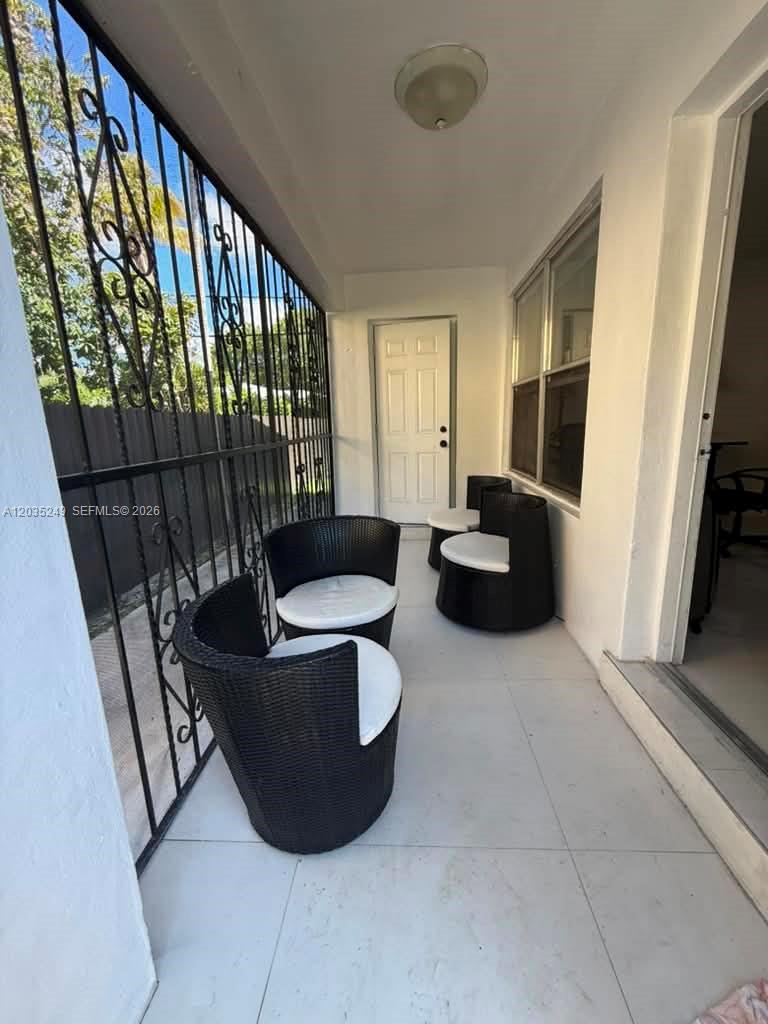 A covered patio features white tile flooring, black wicker chairs, and a metal security gate — 78 NE 43rd St # 0, Miami FL 33137, MIAMI, FL
