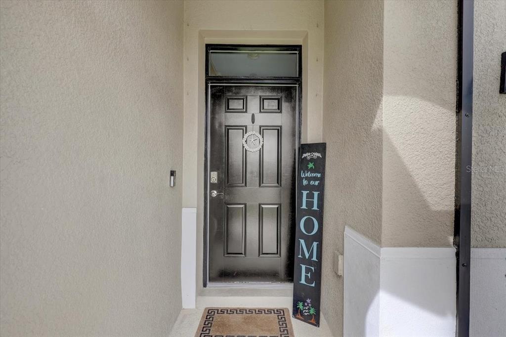 A black front door with a transom window and a vertical welcome sign — 3921 MOSSY LIMB COURT, PALMETTO, FL