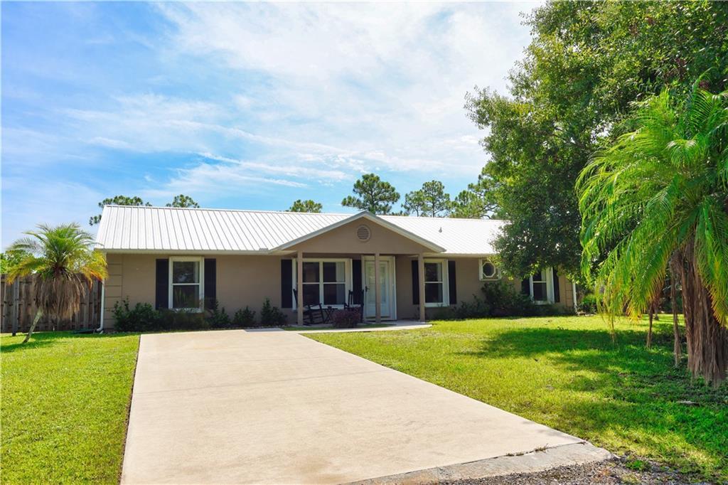 A single-story house with a white metal roof, tan siding, and a concrete driveway — 12050 138th Avenue, Fellsmere FL 32948, FELLSMERE, FL