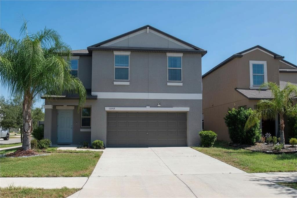 A two-story gray house with a two-car garage and a palm tree in the yard — 10202 COOL WATERLILY AVENUE, RIVERVIEW, FL