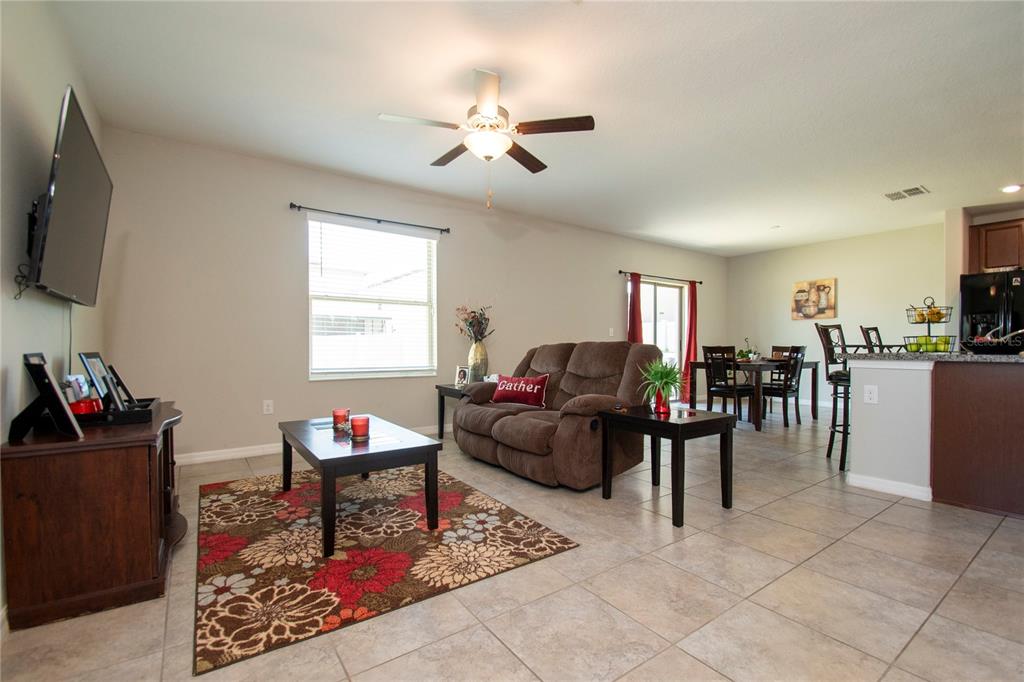 An open-concept living and dining area features tile flooring, a ceiling fan, and furniture — 10202 COOL WATERLILY AVENUE, RIVERVIEW, FL