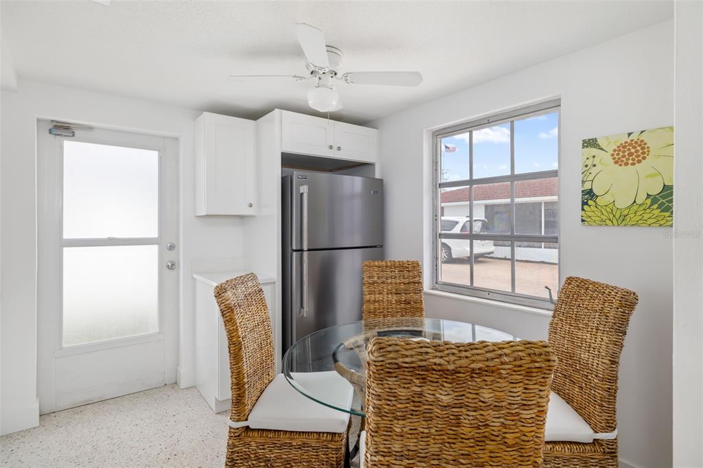 A dining area features a glass-topped table, wicker chairs, a stainless steel refrigerator, and a window — 6154 MIDNIGHT PASS ROAD UNIT A-3, SARASOTA, FL
