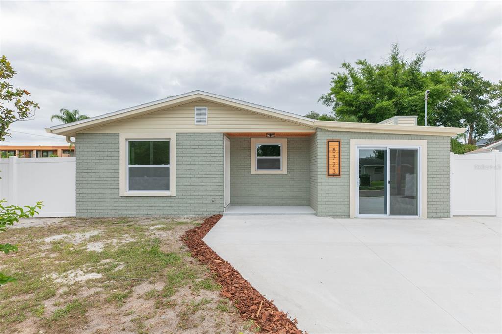 A single-story house with light green brick, a concrete driveway, and a white fence — 8723 N RIVER FOREST CIRCLE, TAMPA, FL