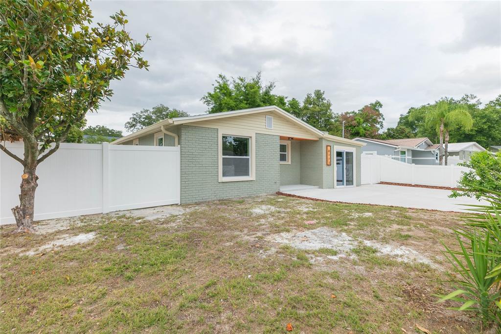 A single-story house with green brick siding, a white vinyl fence, and a concrete driveway — 8723 N RIVER FOREST CIRCLE, TAMPA, FL