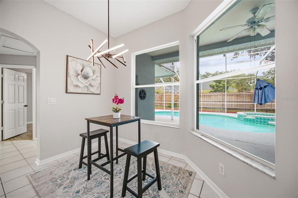 A dining nook features a small table, modern light fixture, and a view of a pool — 4634 RIVER OVERLOOK DRIVE, VALRICO, FL