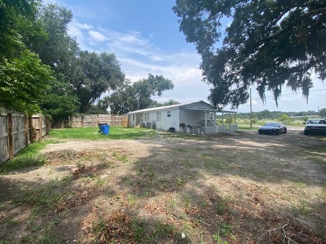 A white mobile home sits on a large, partially dirt lot with two parked cars — 10838 MAIN STREET, THONOTOSASSA, FL