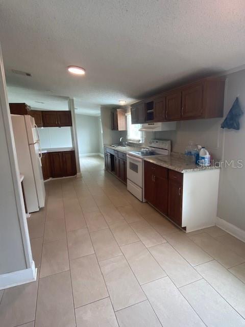 A kitchen with wood cabinets, light countertops, and light-colored tile flooring — 10838 MAIN STREET, THONOTOSASSA, FL