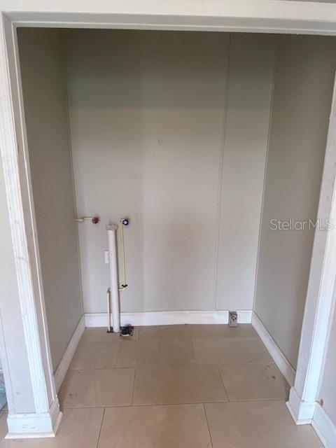 An empty laundry closet with tile flooring, plumbing hookups, and a drain pipe — 10838 MAIN STREET, THONOTOSASSA, FL