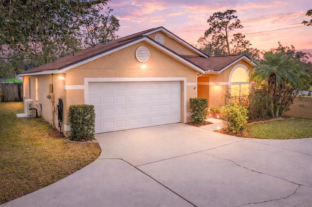 A single-story house with a tan stucco exterior, a two-car garage, and a concrete driveway — 1801 CONCORD DRIVE, APOPKA, FL