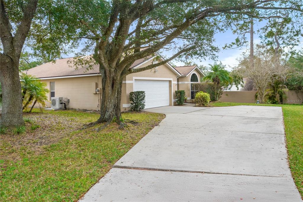 A single-story house with a white garage door, tan stucco siding, and a concrete driveway — 1801 CONCORD DRIVE, APOPKA, FL