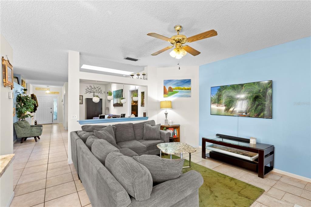 A living room features a gray sectional sofa, a television on a blue wall, and tile flooring — 1801 CONCORD DRIVE, APOPKA, FL