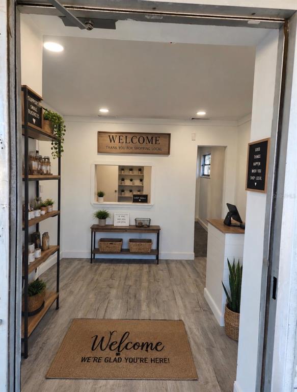 This interior view shows a retail shop entrance with wood-look flooring, shelving, and a welcome mat — 1780 E DUVAL STREET UNIT 6, LAKE CITY, FL