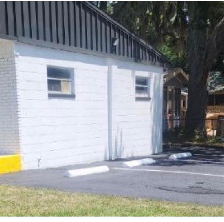 The exterior of a white concrete block building features two windows and a paved parking area — 1780 E DUVAL STREET UNIT 6, LAKE CITY, FL