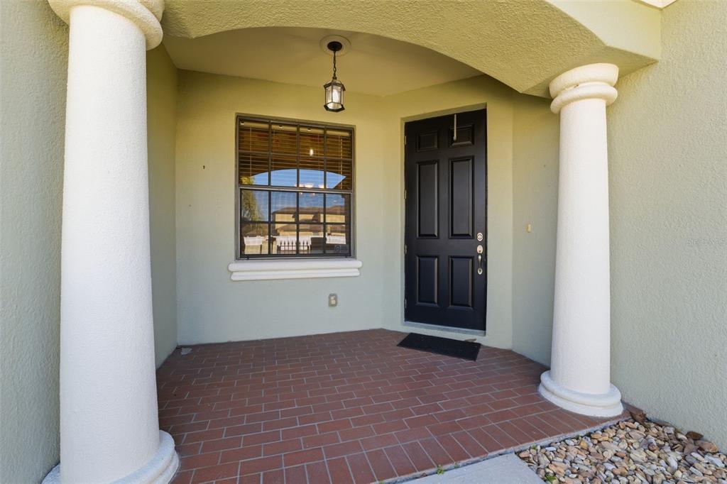 A covered front porch features a black door, a window, and two white columns — 9255 SOUTHERN CHARM CIRCLE, BROOKSVILLE, FL