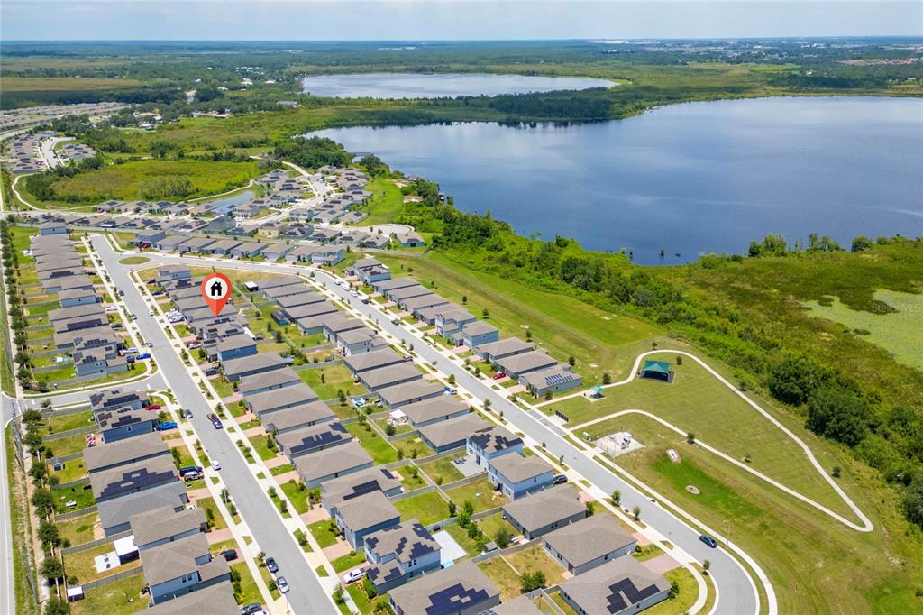 An aerial view shows a suburban neighborhood with houses, streets, and a large lake nearby — 3053 CASSIDY LANE, HAINES CITY, FL