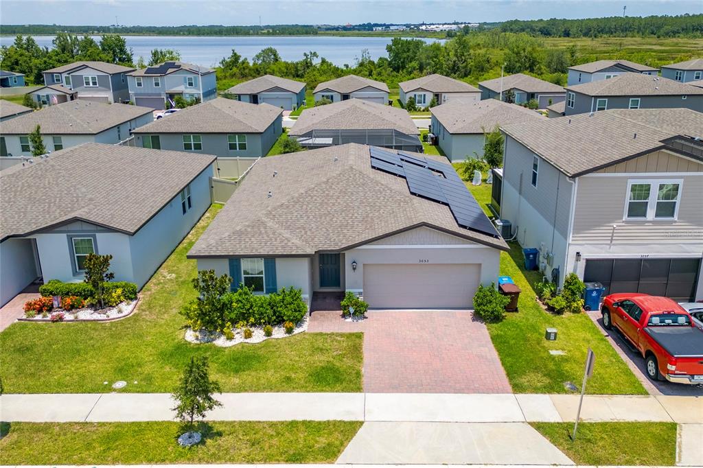 An aerial view shows a suburban house with solar panels on the roof and driveway — 3053 CASSIDY LANE, HAINES CITY, FL