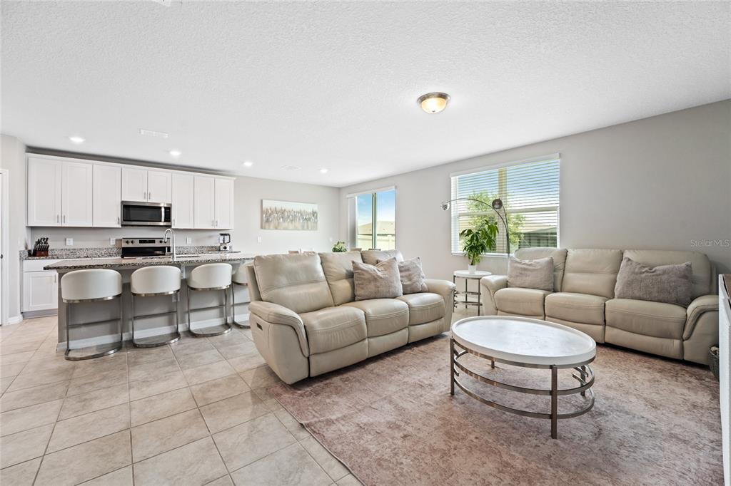 A living room with light-colored sofas and a kitchen with white cabinets and bar seating — 3053 CASSIDY LANE, HAINES CITY, FL