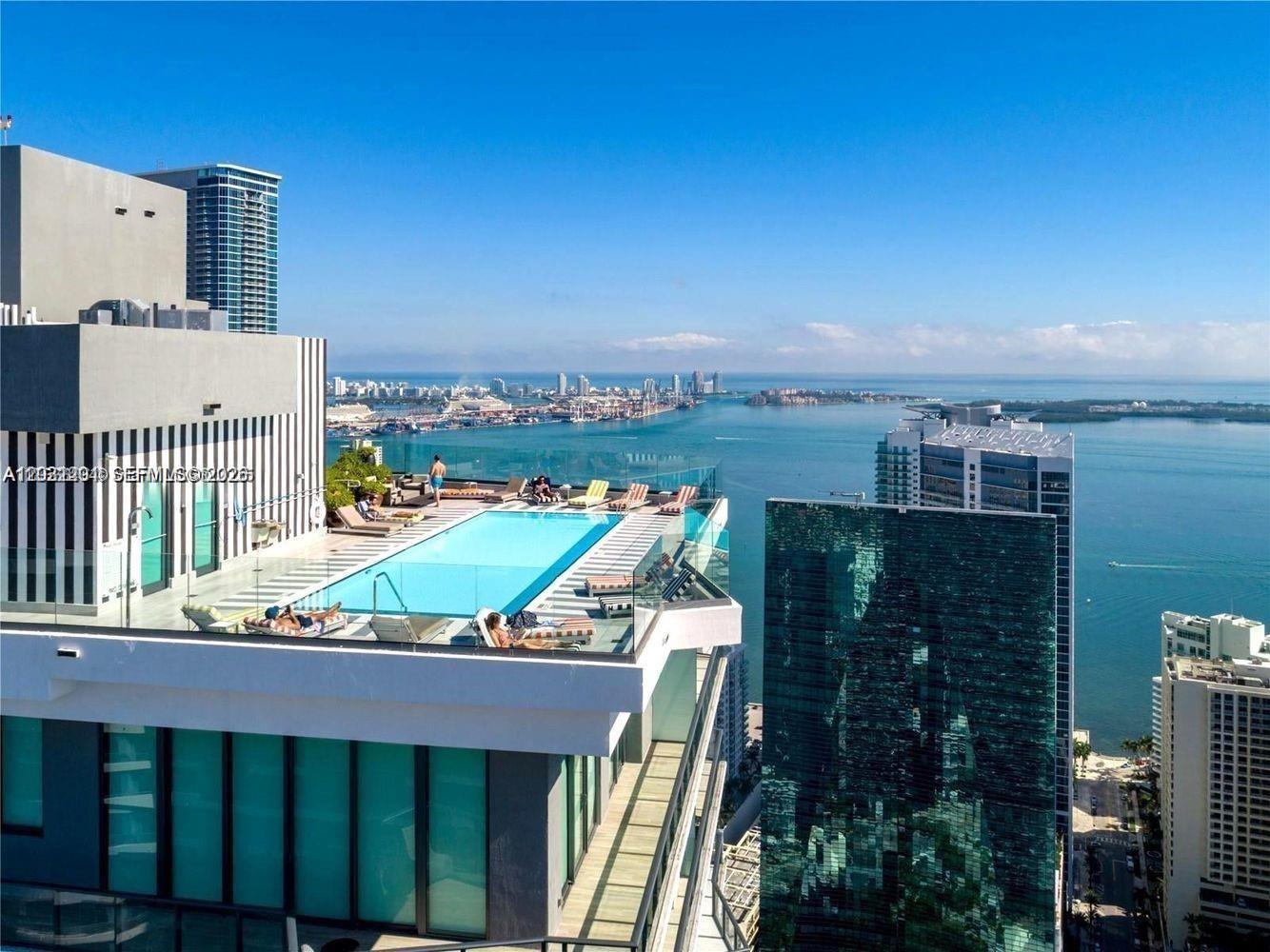 A high-rise balcony with glass railings overlooks a city skyline and the ocean — 1300 S Miami Ave # 3709, Miami FL 33130, MIAMI, FL