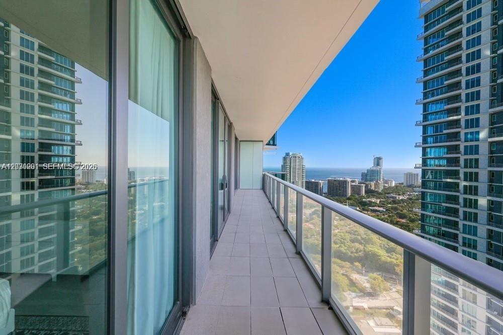 A modern kitchen features light wood cabinetry, a central island, and stainless steel appliances — 1300 S Miami Ave # 3709, Miami FL 33130, MIAMI, FL