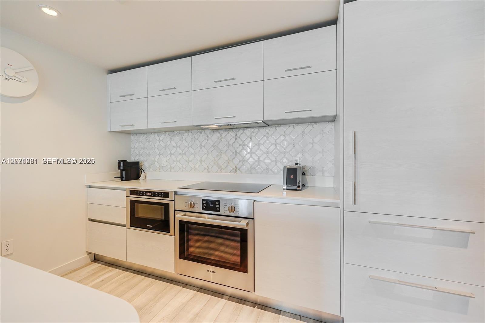 A modern kitchen features white cabinetry, stainless steel appliances, and a patterned tile backsplash — 1300 S Miami Ave # 3709, Miami FL 33130, MIAMI, FL