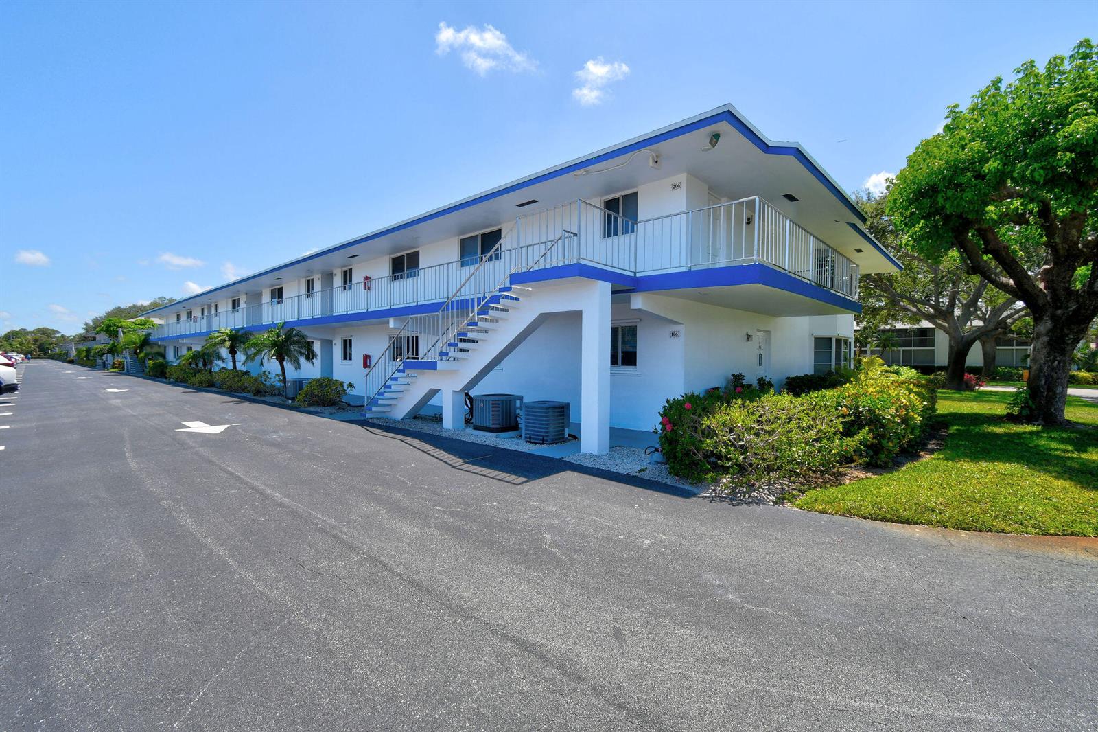 A two-story apartment building features white exterior walls, blue trim, and an outdoor staircase — 9 Garden Street # 204j, Tequesta FL 33469, TEQUESTA, FL