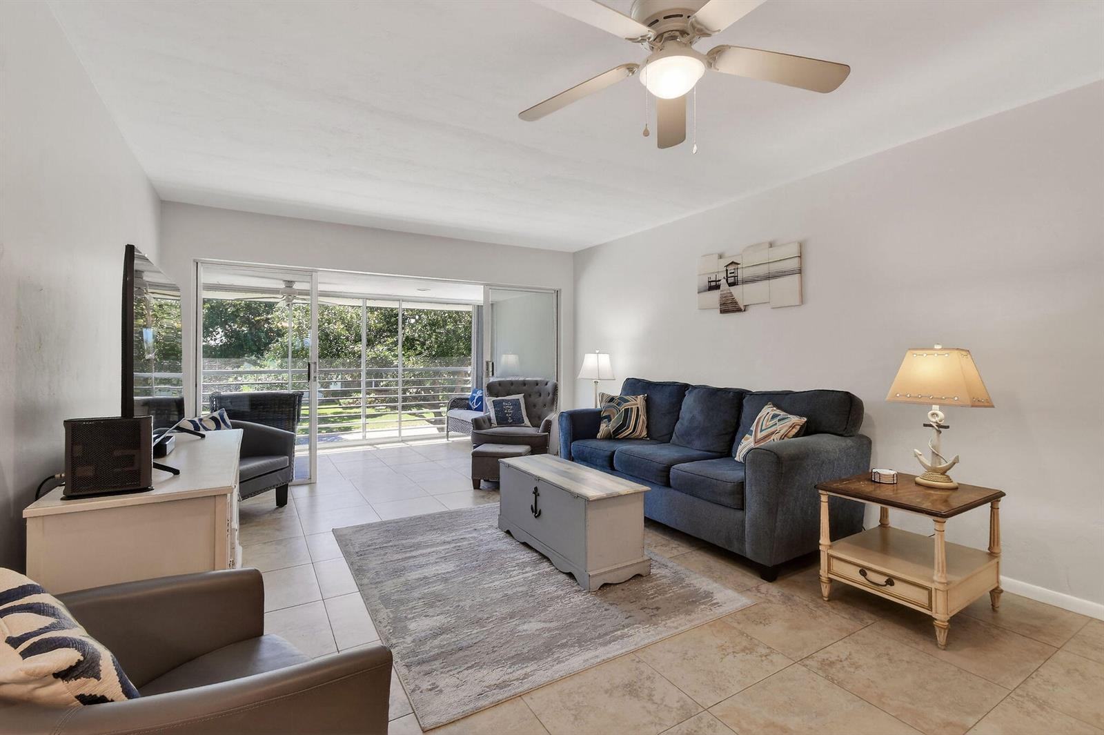 A living room features a blue sofa, a gray area rug, and sliding glass doors — 9 Garden Street # 204j, Tequesta FL 33469, TEQUESTA, FL