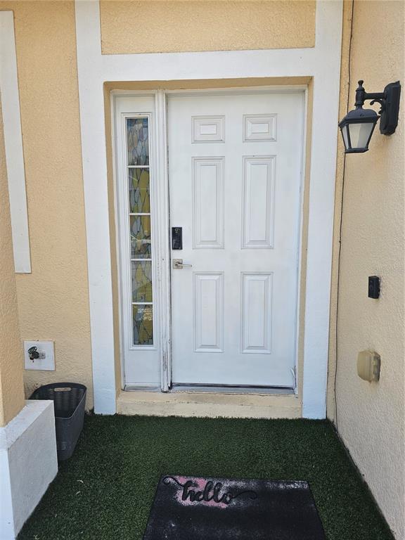 A white front door with a stained glass sidelight sits on a small porch — 2456 TEMPLE GROVE LANE, KISSIMMEE, FL
