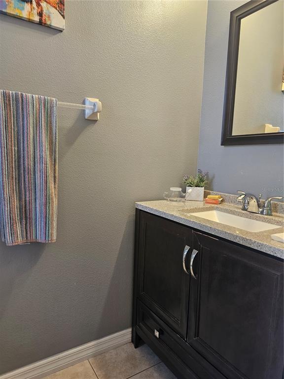 A bathroom features a dark wood vanity, granite countertop, and a striped towel on the wall — 2456 TEMPLE GROVE LANE, KISSIMMEE, FL