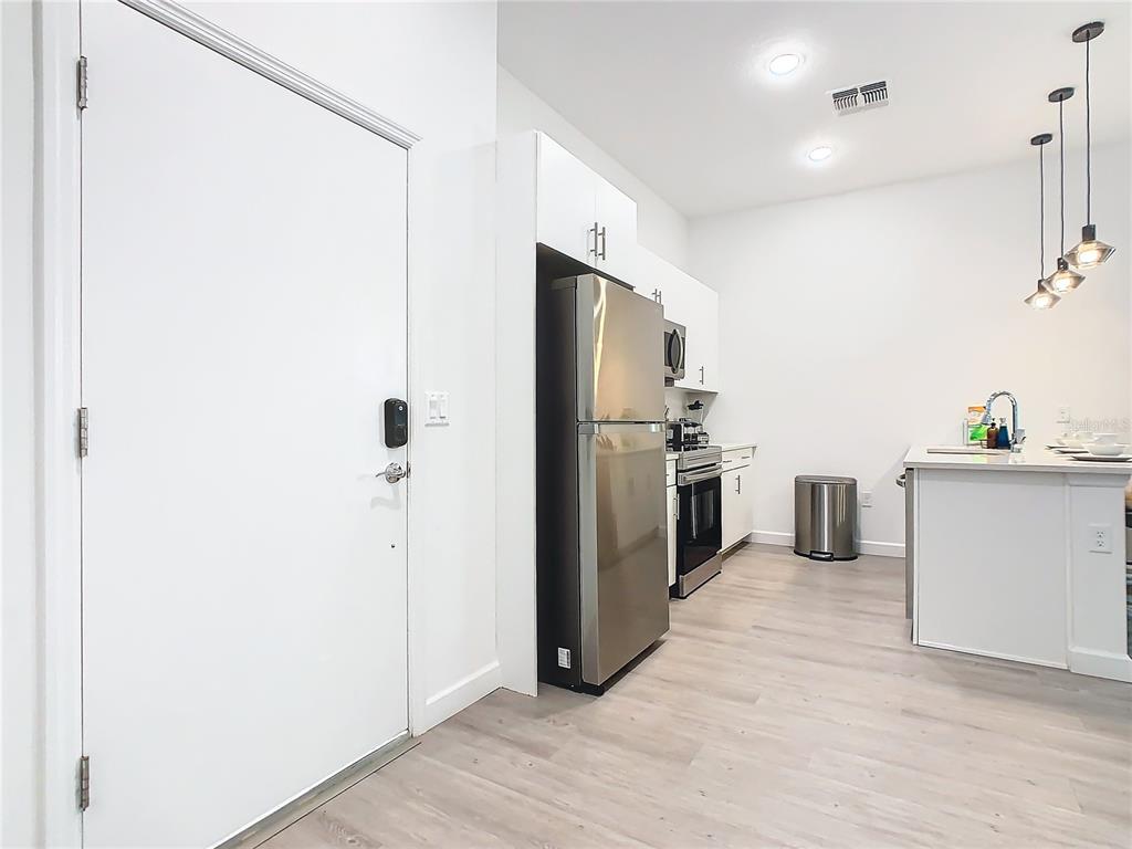 A modern kitchen features stainless steel appliances, white cabinetry, and a kitchen island with pendant lighting — 653 TRIKOMO DRIVE, DAVENPORT, FL