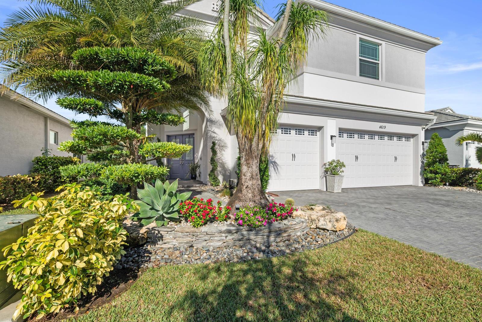 A two-story house features a paved driveway, a stone garden bed, and palm trees — 4619 Citron Way, Westlake FL 33470, WESTLAKE, FL