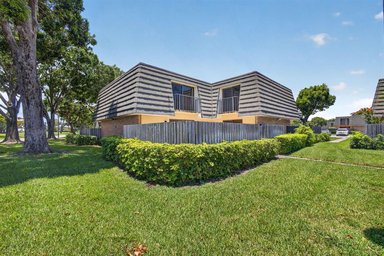 A two-story residential building with a mansard roof, balconies, and a wooden privacy fence — 2101 21st Way, West Palm Beach FL 33407, WEST PALM BEACH, FL