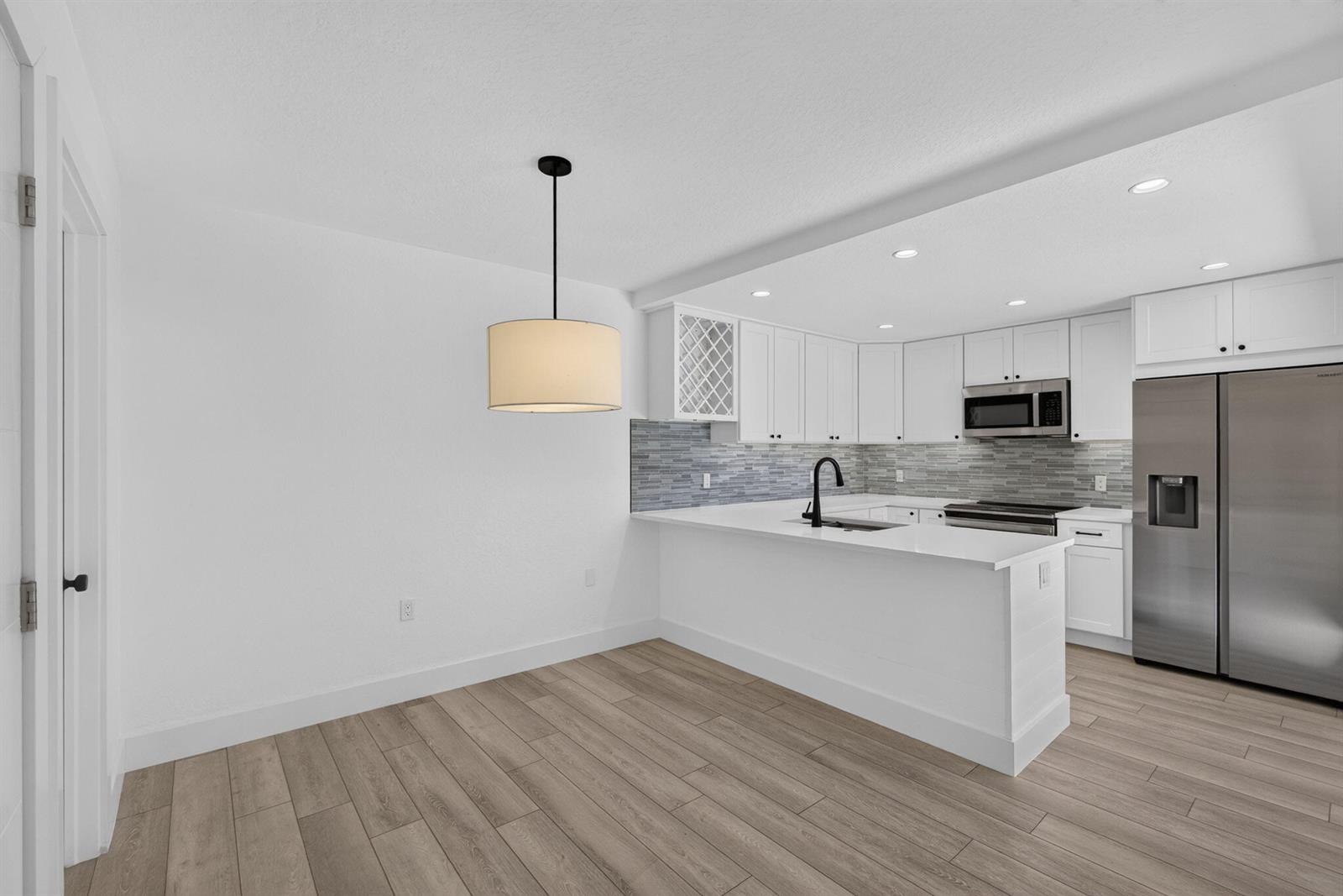 A kitchen with white cabinets, stainless steel appliances, and a breakfast bar next to dining — 2101 21st Way, West Palm Beach FL 33407, WEST PALM BEACH, FL