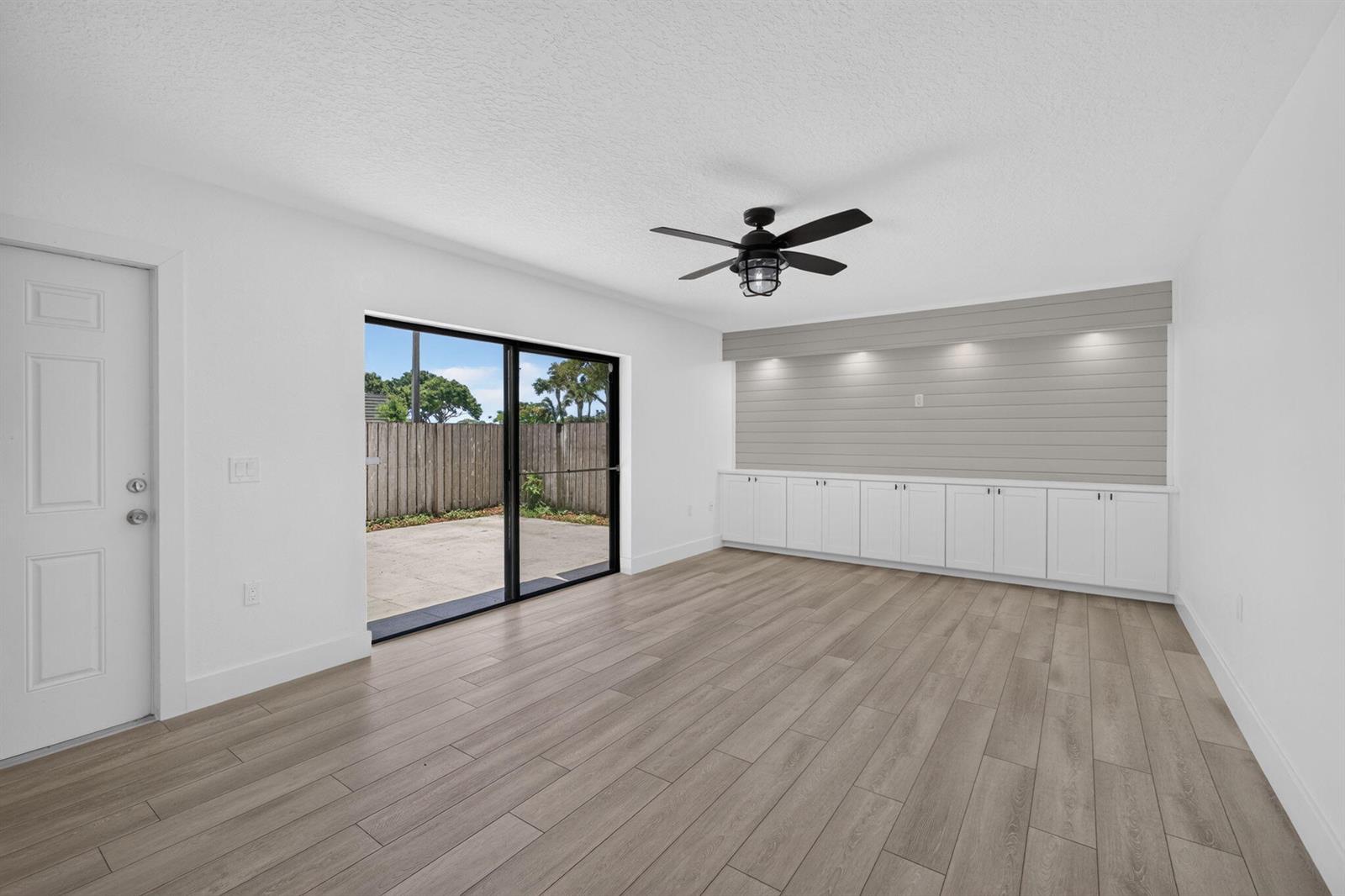A bright room features white walls, wood-look flooring, a ceiling fan, and built-in storage cabinets — 2101 21st Way, West Palm Beach FL 33407, WEST PALM BEACH, FL