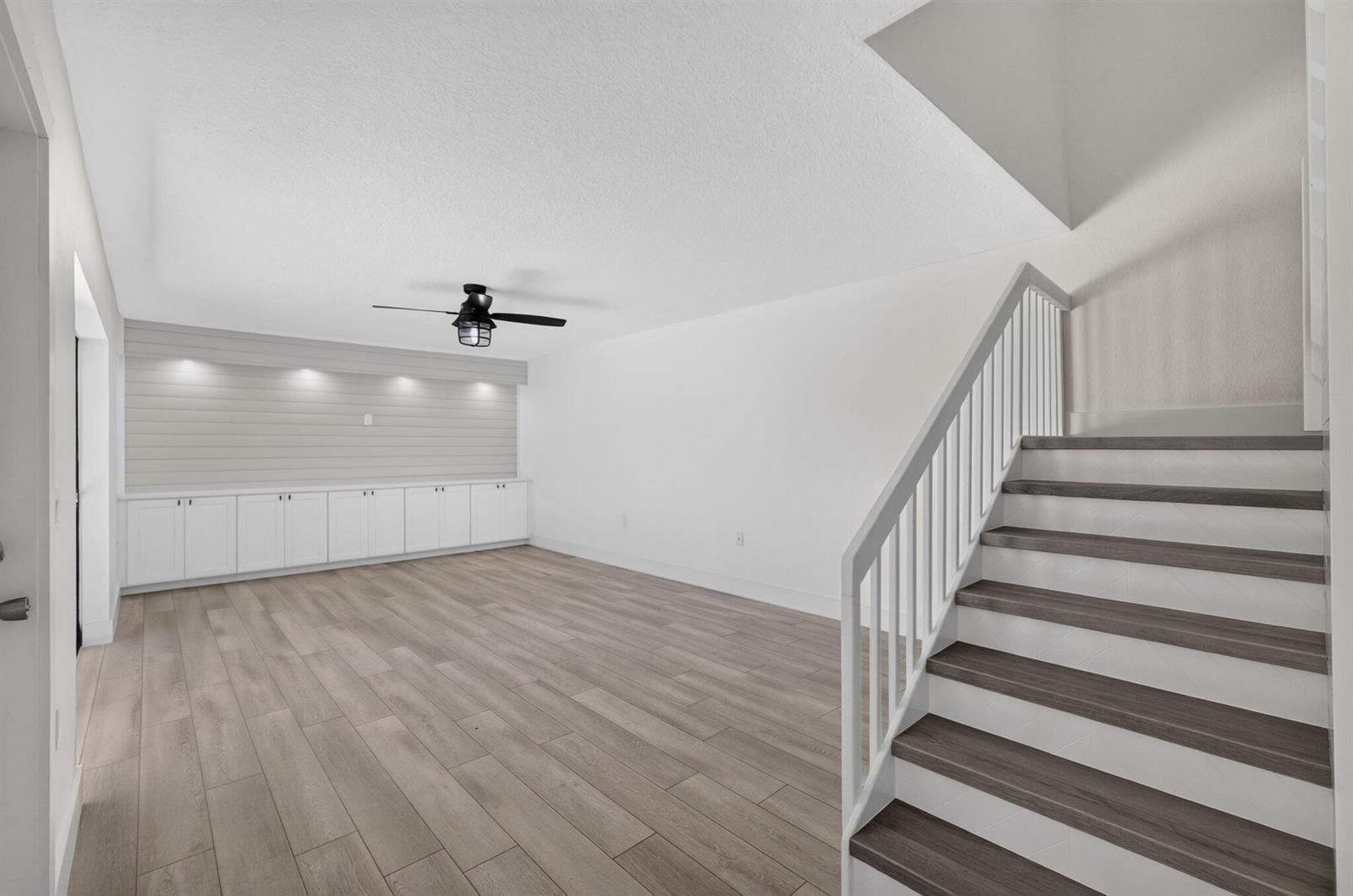 A room with light wood flooring, white cabinets, shiplap wall accents, and a staircase — 2101 21st Way, West Palm Beach FL 33407, WEST PALM BEACH, FL