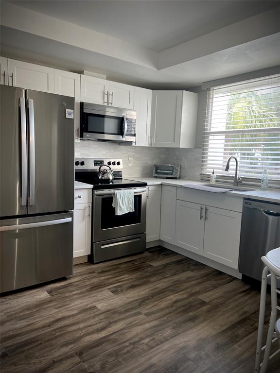 A kitchen features white cabinets, stainless steel appliances, and wood-look flooring — 5110 MARSH FIELD ROAD UNIT 68, SARASOTA, FL