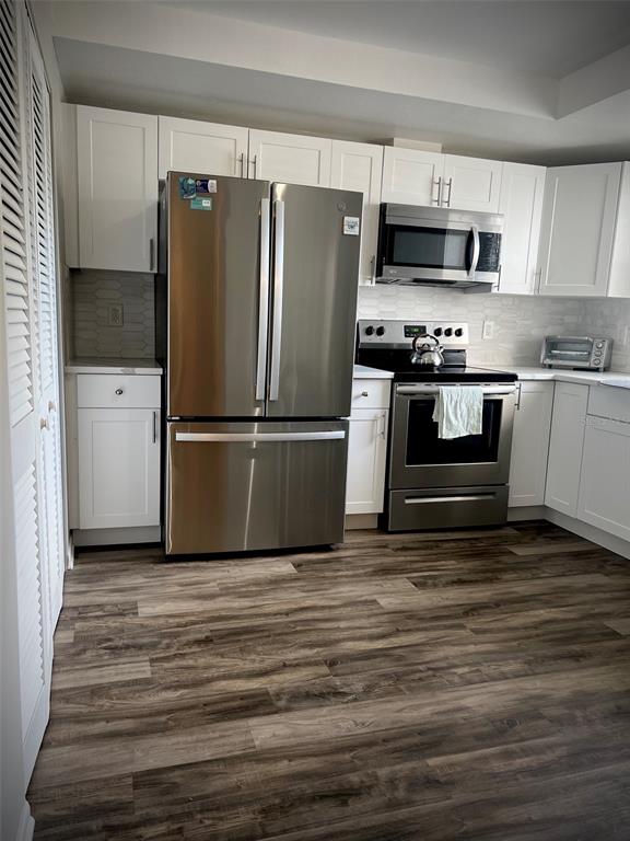 A kitchen with white cabinets, stainless steel appliances, and wood-look flooring — 5110 MARSH FIELD ROAD UNIT 68, SARASOTA, FL