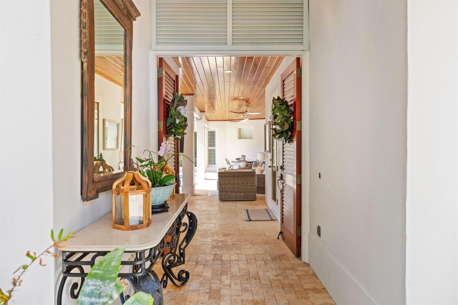 A stone-floored entryway leads through wooden louvered doors to a covered outdoor patio area — 906 Jasmine Lane, Vero Beach FL 32963, VERO BEACH, FL