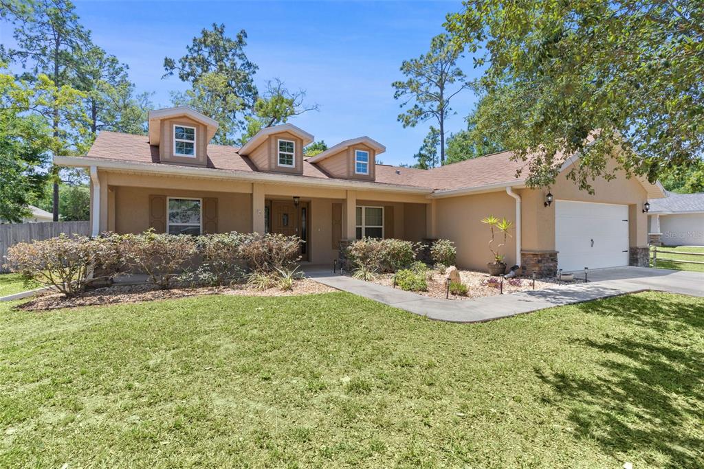 A single-story house with a tan stucco exterior, three dormer windows, and an attached garage — 8770 SE 161ST STREET, SUMMERFIELD, FL