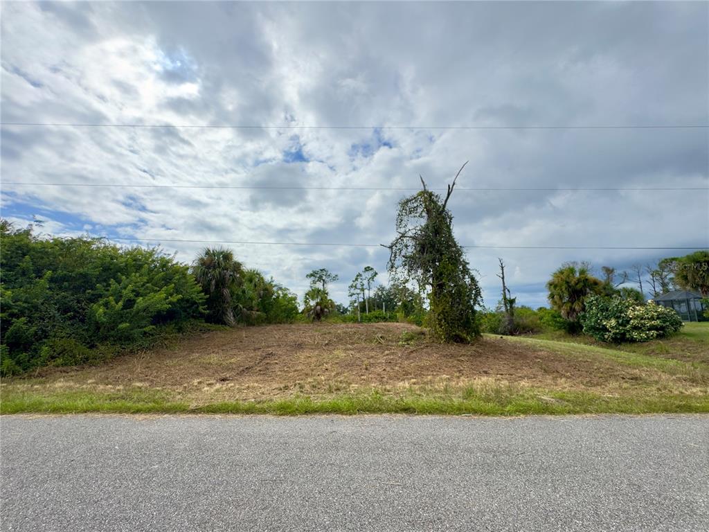 A cleared, vacant lot sits along a paved road under a cloudy sky — LOT 28 FLORALA STREET, NORTH PORT, FL