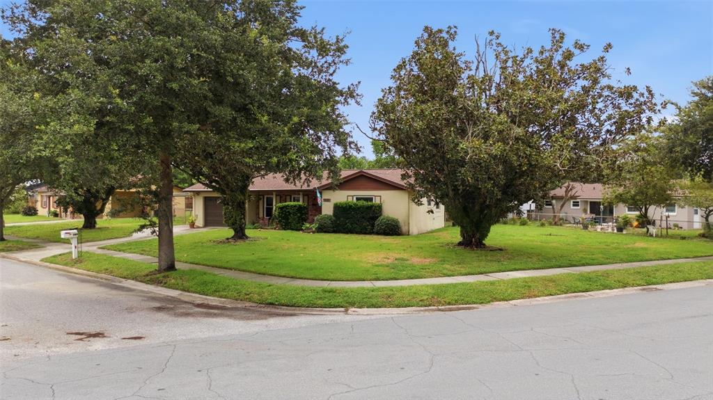 A single-story house with a tan exterior and a large lawn sits on a corner lot — 530 E FOOTHILL WAY, CASSELBERRY, FL