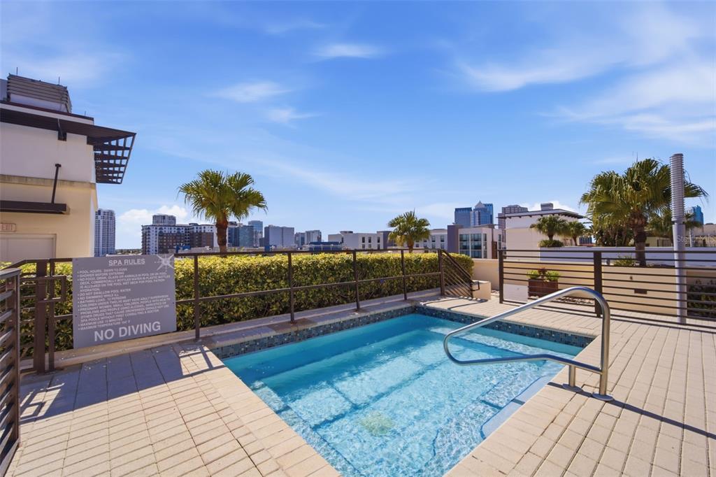 A rooftop hot tub with a metal railing overlooks a city skyline under a clear sky — 1208 E KENNEDY BOULEVARD UNIT 1121, TAMPA, FL