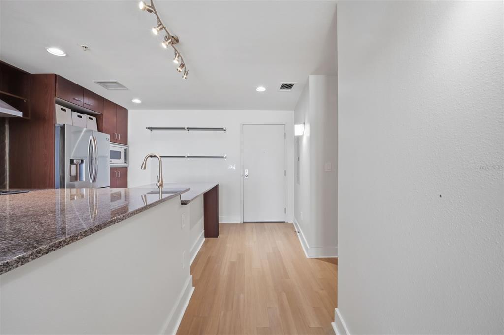 A kitchen with dark wood cabinets, granite countertops, and light wood flooring near an entryway — 1208 E KENNEDY BOULEVARD UNIT 1121, TAMPA, FL