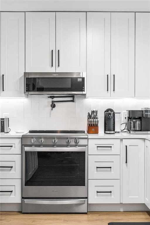 A kitchen features white shaker cabinets, stainless steel appliances, and a white subway tile backsplash — 4501 S ATLANTIC AVENUE UNIT 213, NEW SMYRNA BEACH, FL
